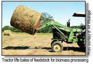 tractor lifting bale of biomass feedstock